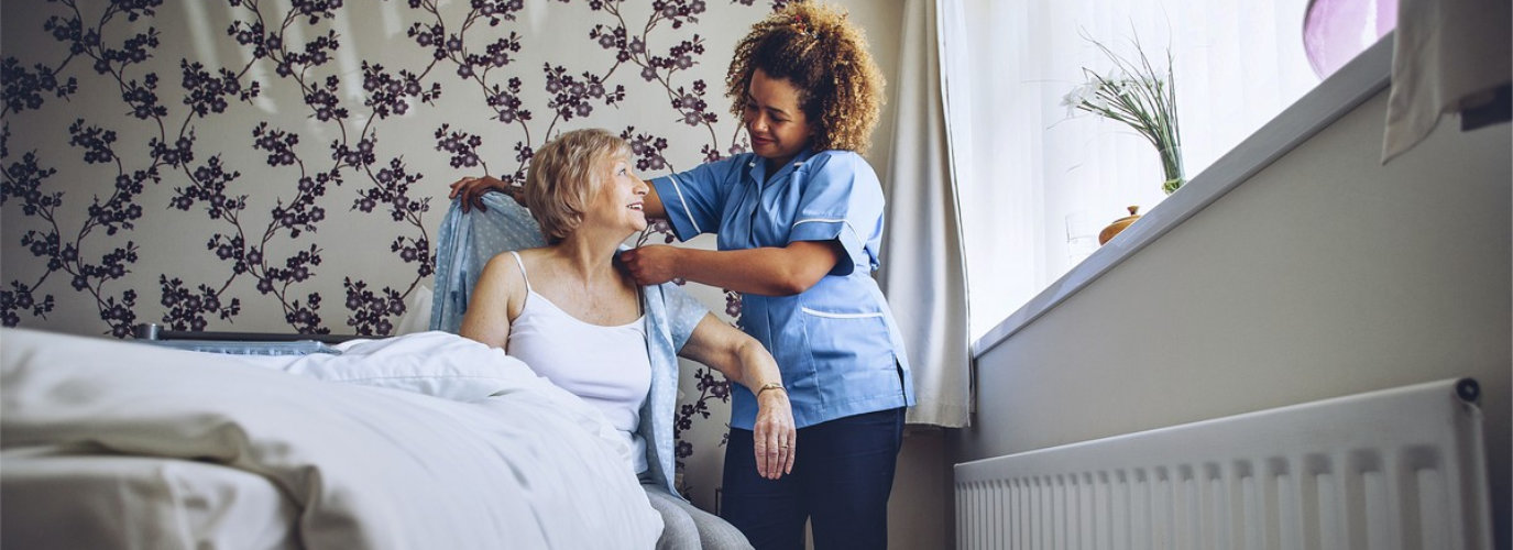 caregiver assiting senior woman to dress up